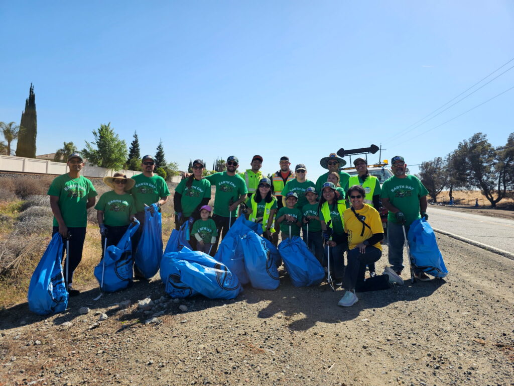 employees smiling holding grabbers and trash bags